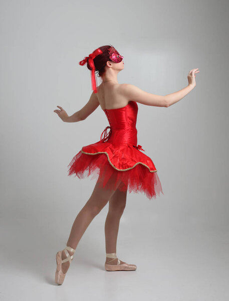 портрет девушки в красной балетной пачке и маске. танцевальная поза на фоне студии
.