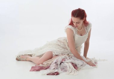 yırtık ve yırtık gelinlik giyen kırmızı saçlı kız tam uzunlukta portre. Beyaz bir stüdyo arka plan karşı Ayakta poz.