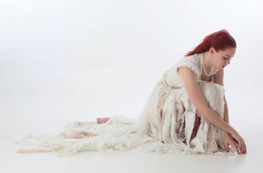 yırtık ve yırtık gelinlik giyen kırmızı saçlı kız tam uzunlukta portre. Beyaz bir stüdyo arka plan karşı Ayakta poz.