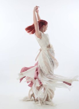 yırtık ve yırtık gelinlik giyen kırmızı saçlı kız tam uzunlukta portre. Beyaz bir stüdyo arka plan karşı Ayakta poz.