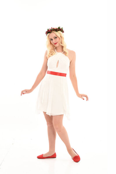 полноразмерный портрет блондинки в белом платье и цветочной короне. Стоя поза, держа красный подарок, изолированы на белом фоне студии
.