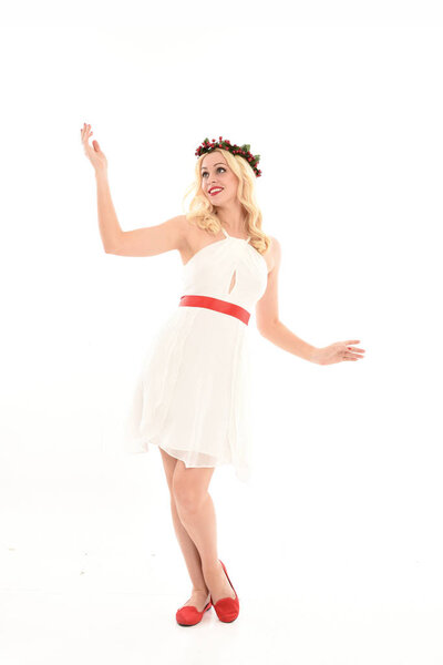 полноразмерный портрет блондинки в белом платье и цветочной короне. Стоя поза, держа красный подарок, изолированы на белом фоне студии
.