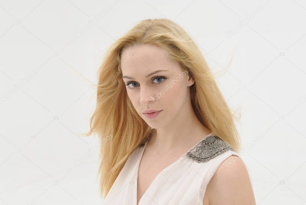 close up portrait of blonde girl with long hair flowing in a win.  isolated against a white studio background.