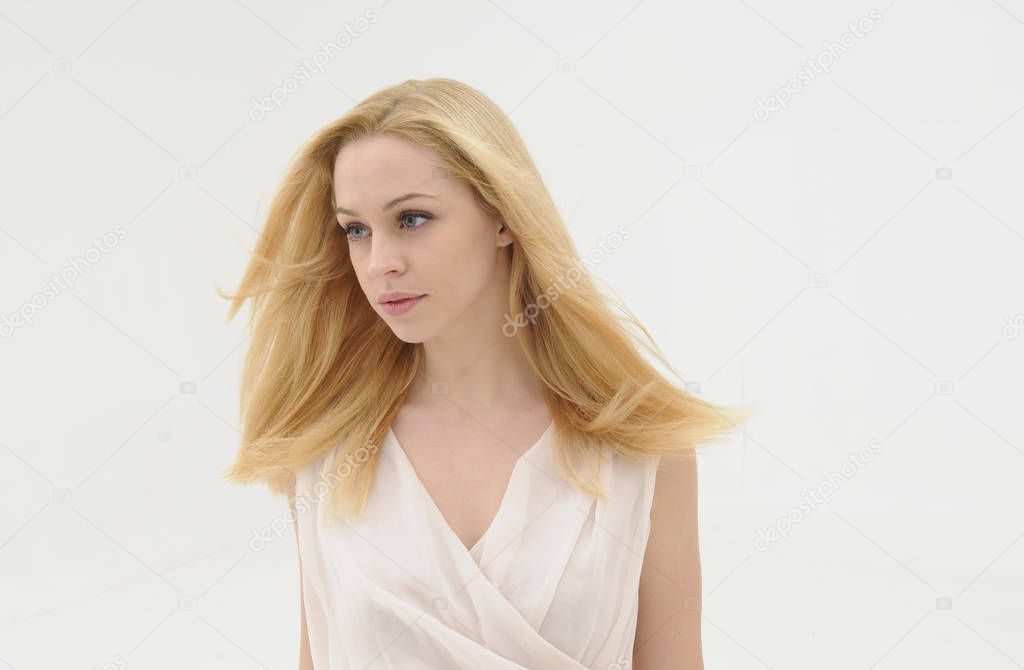 close up portrait of blonde girl with long hair flowing in a win.  isolated against a white studio background.