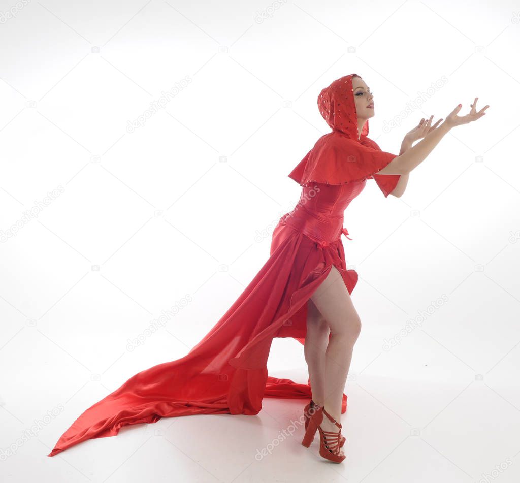 full length portrait of woman wearing red riding hook cloak and long silk gown. standing pose, isolated on white studio background