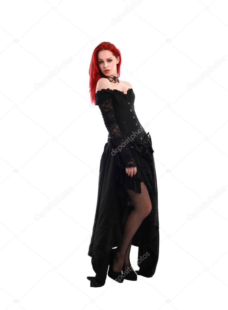 full length portrait of a  red haired girl wearing a  black gothic gown, Standing pose on a grey studio background.