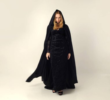 kravat ve ekose etek ile kırmızı hırka giyen sarışın kız tam uzunlukta portre, okul üniforması, beyaz bir stüdyo arka plan üzerinde, kameradan uzağa bakan poz ayakta.