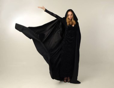 kravat ve ekose etek ile kırmızı hırka giyen sarışın kız tam uzunlukta portre, okul üniforması, beyaz bir stüdyo arka plan üzerinde, kameradan uzağa bakan poz ayakta.