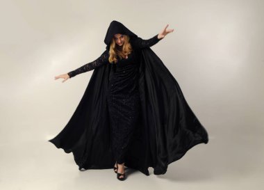 kravat ve ekose etek ile kırmızı hırka giyen sarışın kız tam uzunlukta portre, okul üniforması, beyaz bir stüdyo arka plan üzerinde, kameradan uzağa bakan poz ayakta.