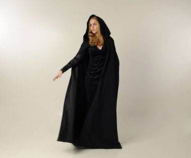 kravat ve ekose etek ile kırmızı hırka giyen sarışın kız tam uzunlukta portre, okul üniforması, beyaz bir stüdyo arka plan üzerinde, kameradan uzağa bakan poz ayakta.