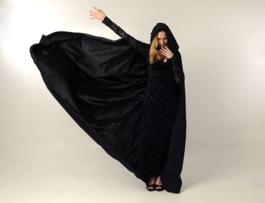 kravat ve ekose etek ile kırmızı hırka giyen sarışın kız tam uzunlukta portre, okul üniforması, beyaz bir stüdyo arka plan üzerinde, kameradan uzağa bakan poz ayakta.