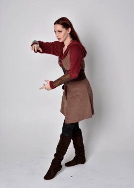 Ortaçağ kostümü giymiş bir kızın tam boy portresi. Gri bir stüdyonun arka planında, elinde kılıçla dikiliyordu..