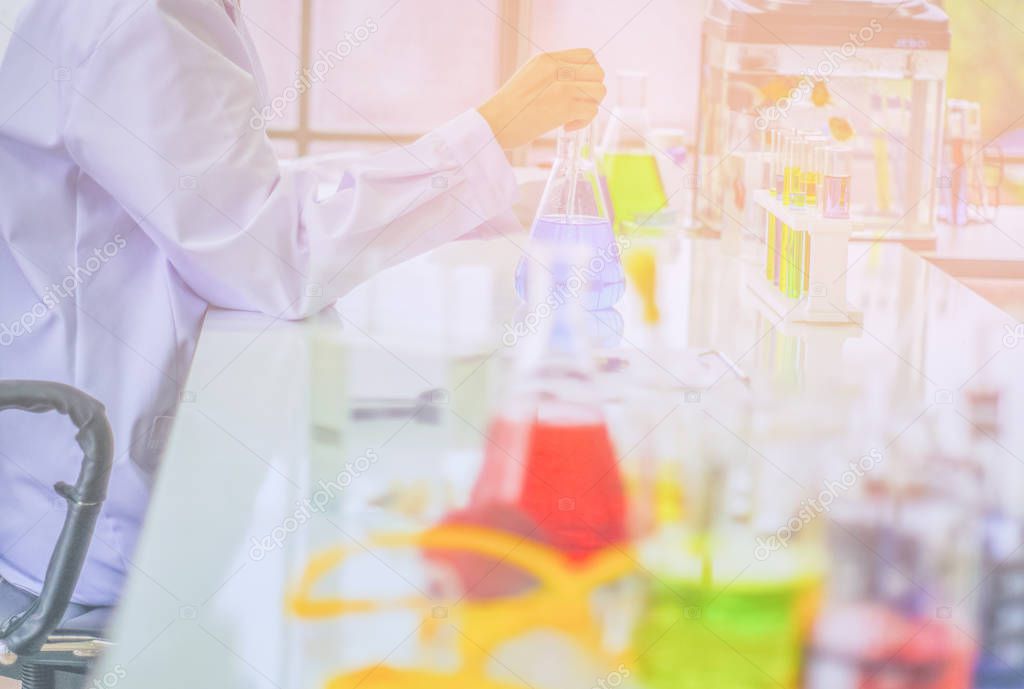 Chemist works at the laboratory, morning  room has sunlight shining through, With test specimens working with colorful liquid chemicals, Glass tubes for cosmetics, To develop safe formulas for consumers.