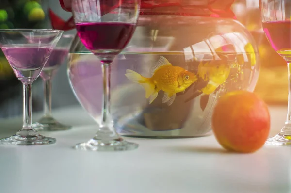 Wine glasses and cocktails and spirits and apples, and goldfish jar, Put on a wooden table at a Christmas party.