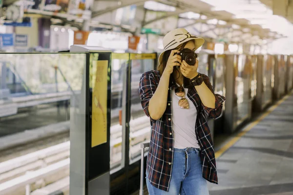 Beautiful women are taking photos while waiting for the train with luggage,With concept of leisure, adventure and travel planner by train,During summer holidays by yourself.