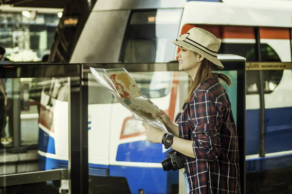 Beautiful women traveling are checking their travel route with a map in hand,With concept of leisure, adventure and travel planner by train,During summer holidays by yourself.