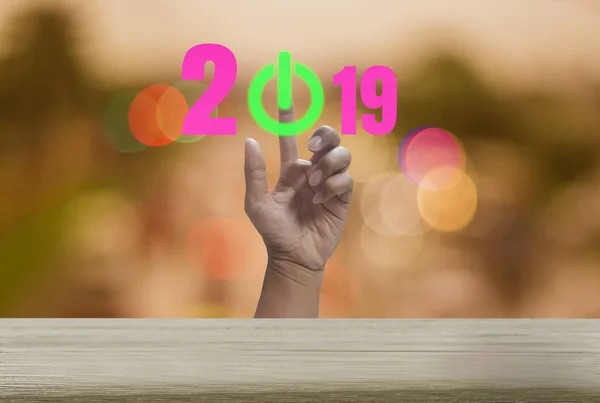 Happy new year with Wood table with bokeh backgrounds sparkling, festival and holiday, abstract concept hand press green button, the symbol of the beginning of the year 2019