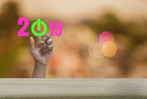 Happy new year with Wood table with bokeh backgrounds sparkling, festival and holiday, abstract concept hand press green button, the symbol of the beginning of the year 2019