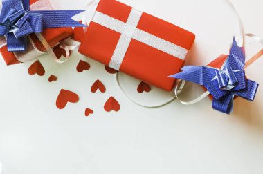 Üstten görünüm Sevgililer günü hediye kırmızı kutuları, kağıt kalp şeklinde, şerit ve mavi yayla beyaz zemin üzerine kutlayan Festivali gün aşık kopya alanı metin girişi için sembolize kavram kümesi.