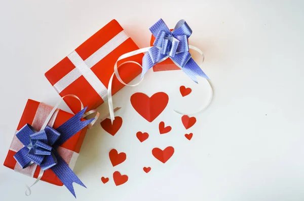 Top view Valentine day set of gift red boxes,with blue bow and ribbon, with paper heart shape,on white background,concept Celebrating festival symbolizes day of love,with copy space for text input.