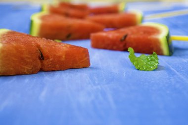 Parlak mavi ahşap arka plan üzerinde karpuz dilimleri ve nane, concep