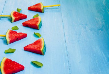 Parlak mavi ahşap arka plan üzerinde karpuz dilimleri ve nane, concep