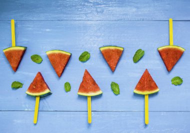 Parlak mavi ahşap arka plan üzerinde karpuz dilimleri ve nane, concep