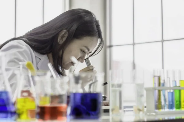 Fiatal vegyész nő néz keresztül mikroszkóp, dolgozik a l — Stock Fotó