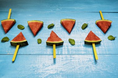 Parlak mavi ahşap arka plan üzerinde karpuz dilimleri ve nane, concep