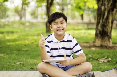 Sevimli gülümseme ile Asya çocuk, elinde tablet ile, Gard ayakta