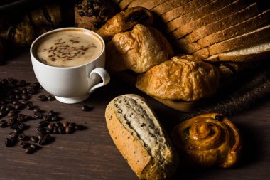 Duman ile beyaz bardak sıcak kahve, fırın ve kahve çekirdekleri ile