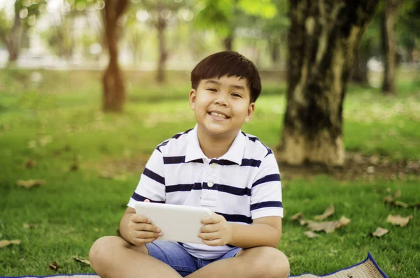 Sevimli gülümseme ile Asya çocuk, elinde tablet ile, Gard ayakta — Stok fotoğraf