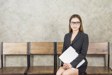 Güzel bir Asyalı kadın beklerken ahşap bir sandalyede oturur