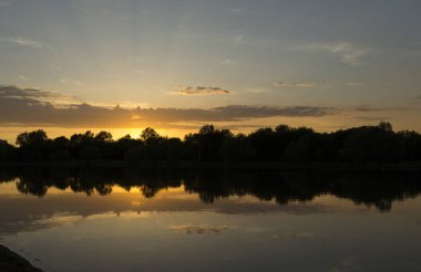 Bir yaz akşamı gölün kıyısında inanılmaz inanılmaz çok renkli gün batımı. Bulutlar suya yansıyor..