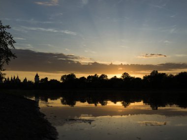 Bir yaz akşamı gölün kıyısında inanılmaz inanılmaz çok renkli gün batımı. Bulutlar suya yansıyor..
