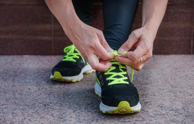 Dişi koşucu ayakkabılarını bağlıyor. Dışarıda koşuya hazırlanıyor..