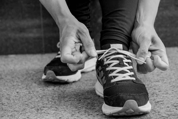 Dişi koşucu ayakkabılarını bağlıyor. Dışarıda koşuya hazırlanıyor..