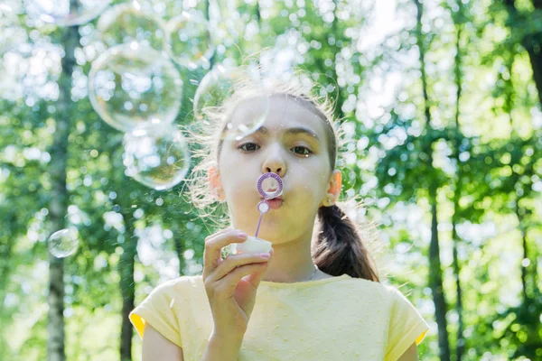 Tatlı küçük kız sabun köpüğü üflüyor..