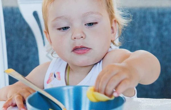 小可爱金发碧眼的女孩吃面食与手 — 图库照片