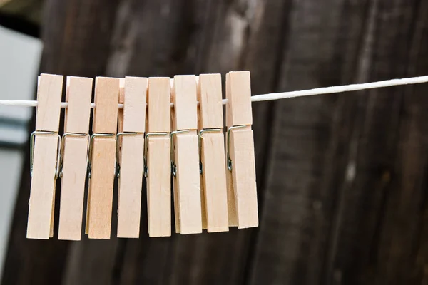wooden clothespins hang on a rope on a wooden background.