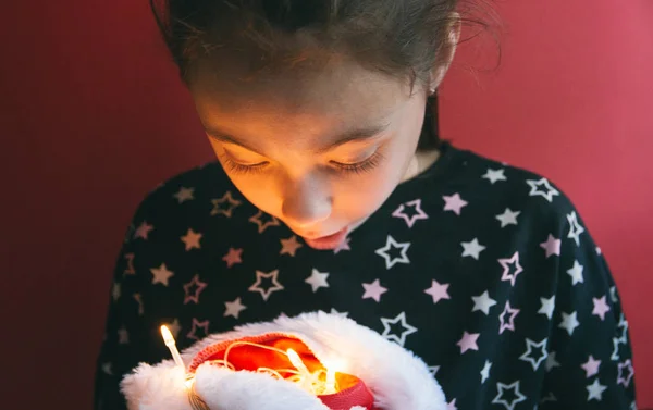 小可爱的女孩举行圣诞老人的帽子与发光的花环内红色背景 — 图库照片