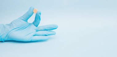 Mavi arka plan ile bir tıp tablet tutan el.