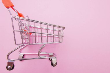 Bazı kopya alanı ile pembe arka plan üzerinde alışveriş arabası.