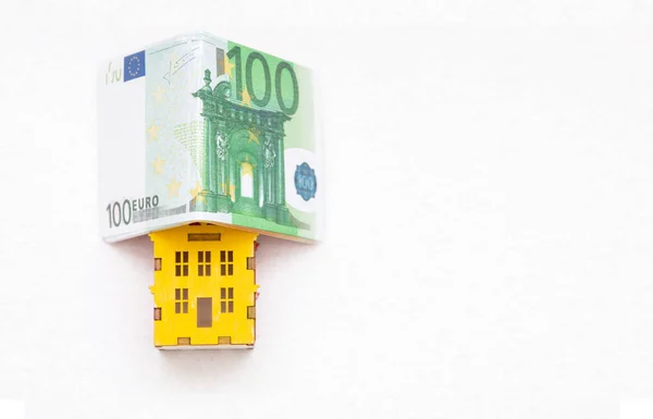 miniature of house under the Euro money folded in the shape of a house isolated on white background.