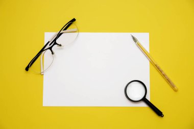 kalem beyaz kağıt Büyüteç gözlük kopya alanı üst sarı zemin üzerine görüntülemek.