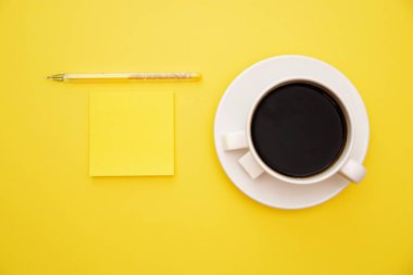 kalem sarı çıkartmalar ve bir fincan kahve kopya alanı üst sarı zemin üzerine görüntülemek.