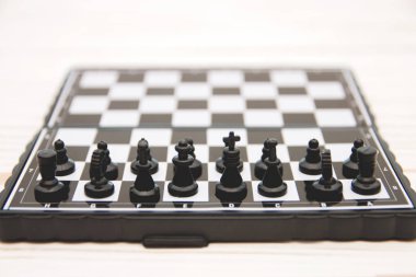 küçük cep satranç, satranç tahtası Beyaz ahşap zemin üzerine yerleştirilmiş plastik satranç taşları