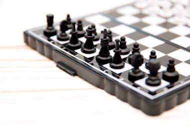 küçük cep satranç, satranç tahtası Beyaz ahşap zemin üzerine yerleştirilmiş plastik satranç taşları