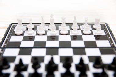 küçük cep satranç, satranç tahtası Beyaz ahşap zemin üzerine yerleştirilmiş plastik satranç taşları