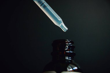 homeopatik ilaç, karanlık bir arka plan yakın çekim bir şişe içine pipet.